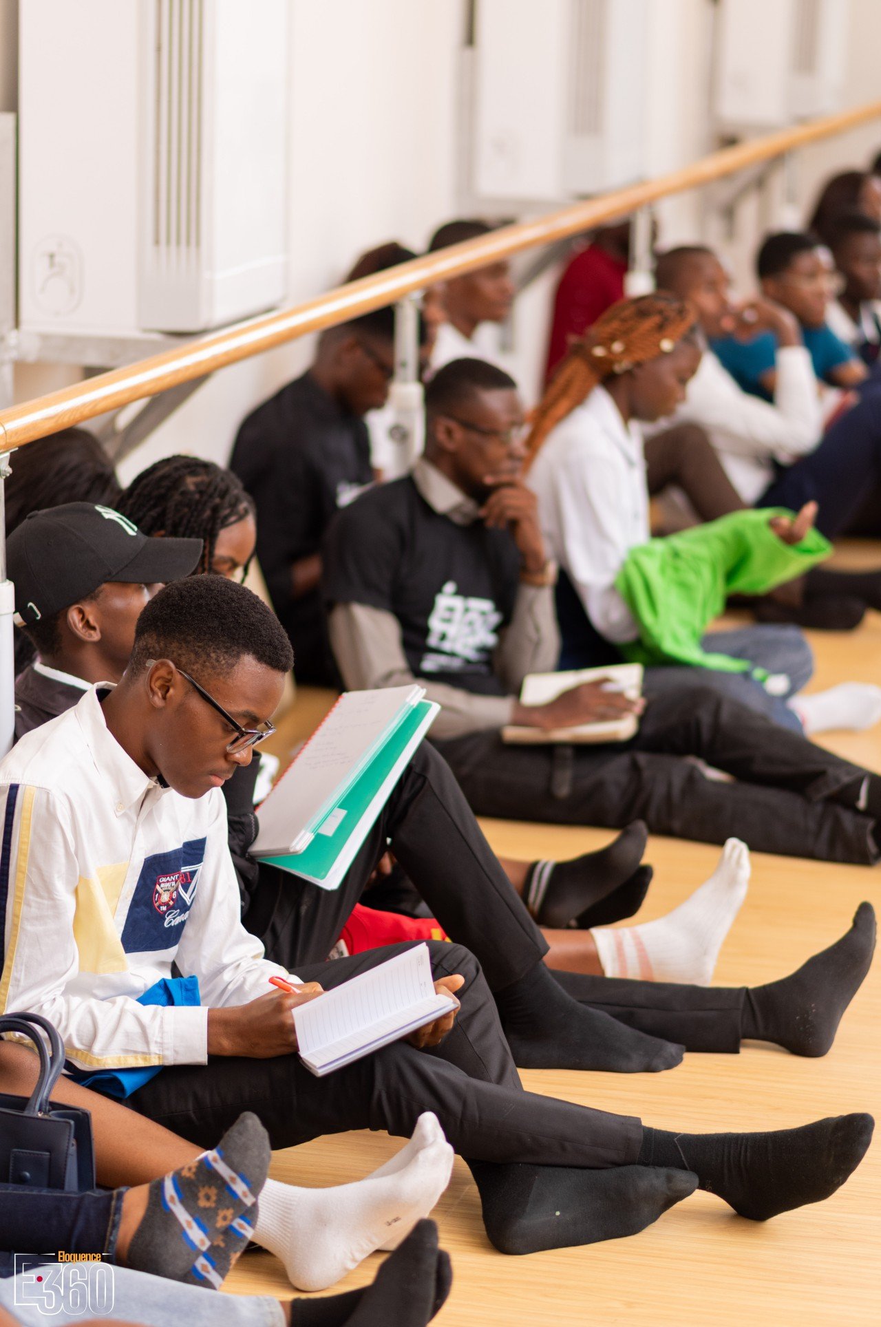 Des participants assis au sol lisent ou écrivent dans leurs carnets.