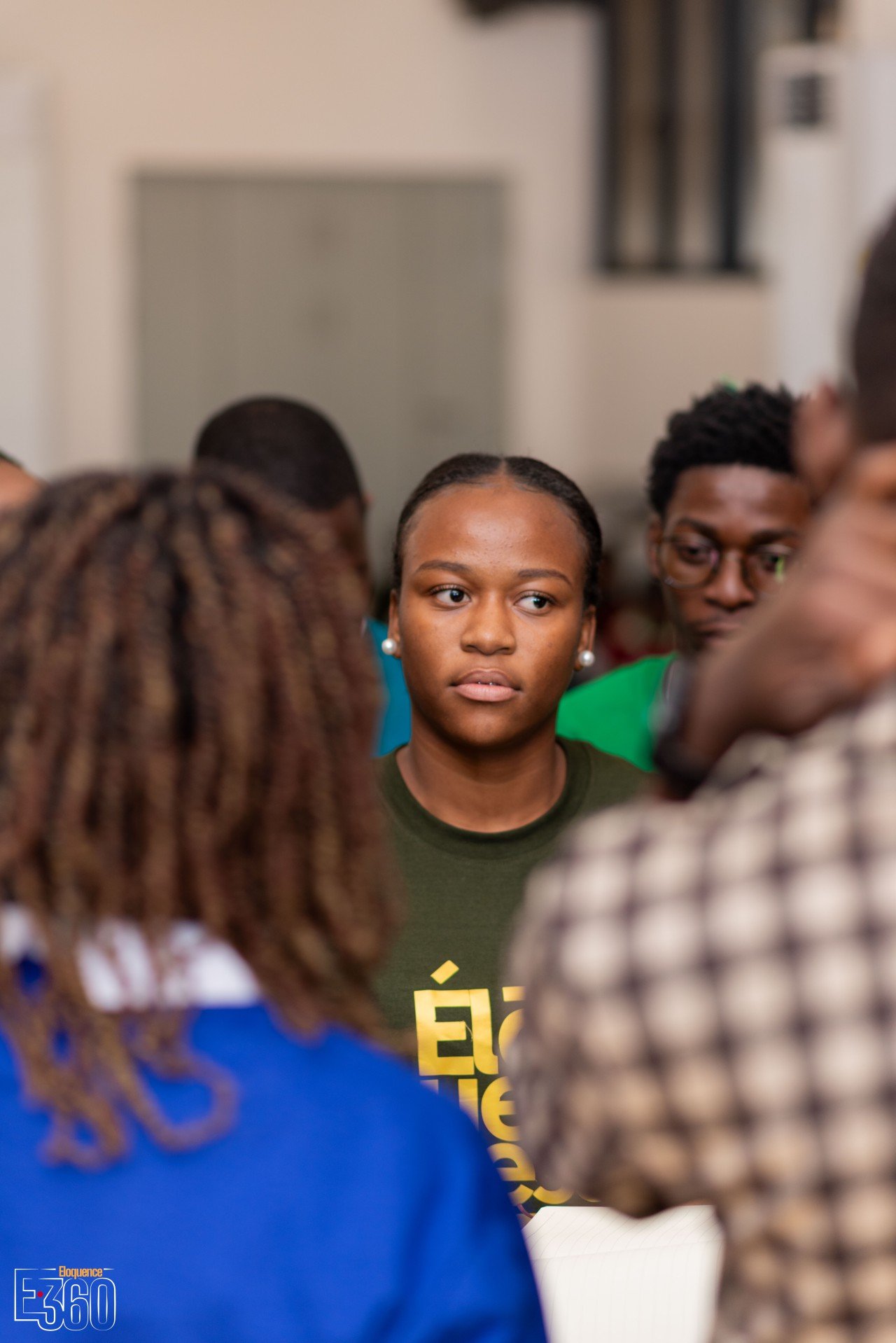 Une participante en haut vert s’exprime, entourée de participants vus de dos.