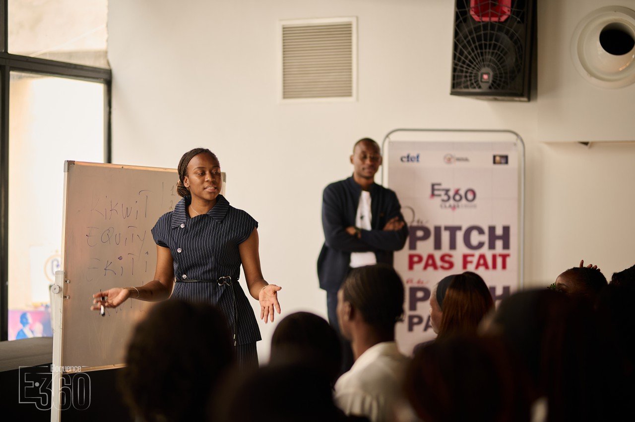 Une participante présente son propos devant un public assis.