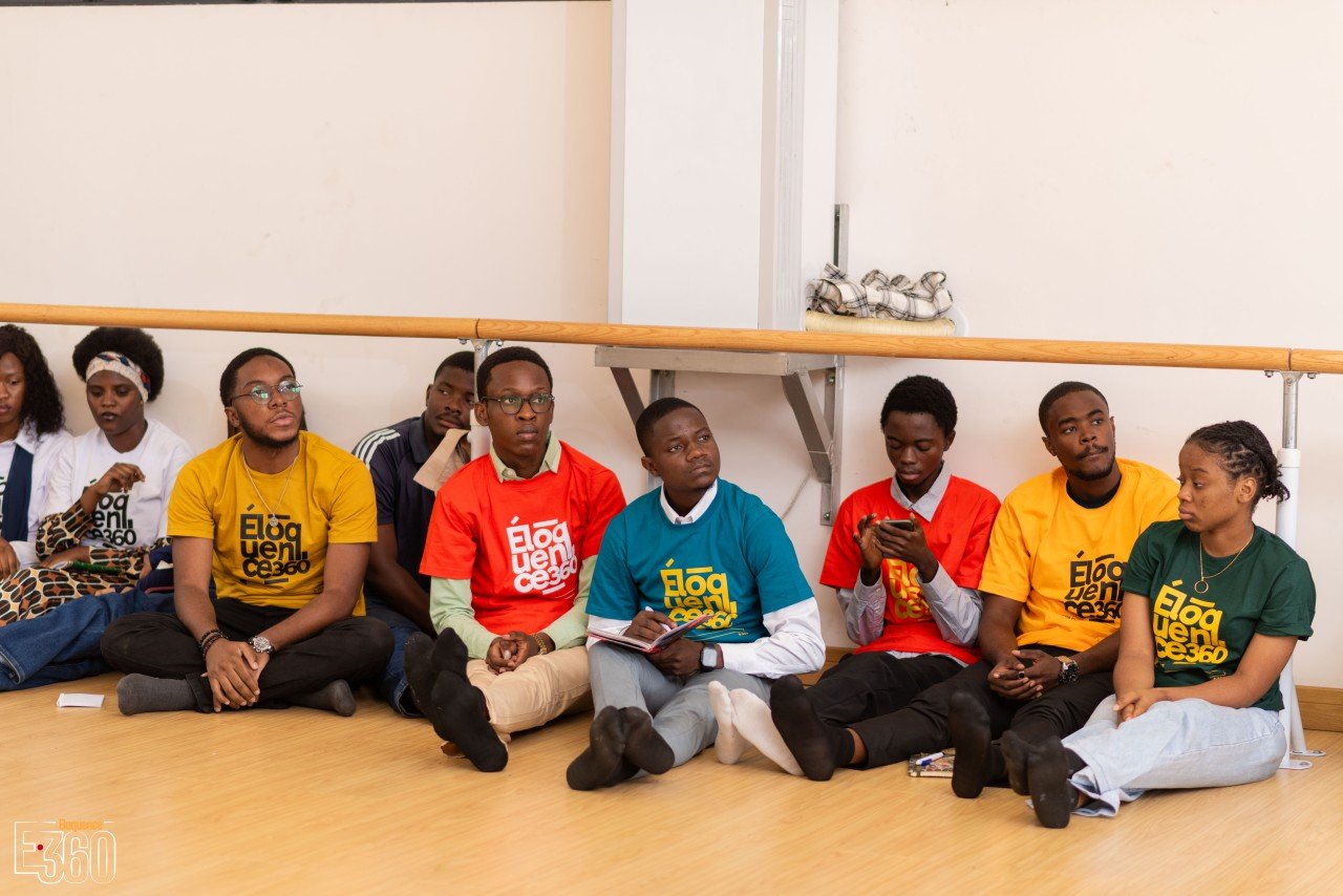Des participants assis côte à côte écoutent dans une salle de travail.